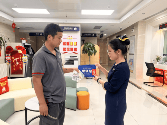 富力城支行工作人员为快递小哥张师傅展示零钱包的多种用途