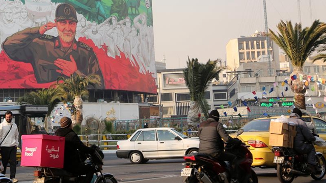  1月6日，在伊朗首都德黑兰街头，车辆经过一幅绘有伊遇袭身亡的高级将领卡西姆·苏莱曼尼形象的宣传海报。新华社